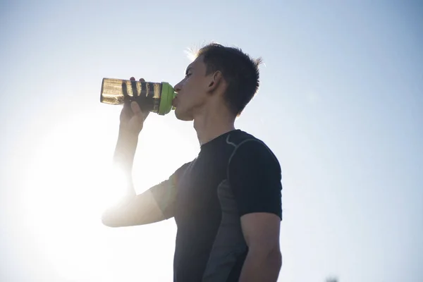 tired athlete man drinking water from a shaker