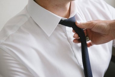 Bir adamın boynuna siyah kravat takan bir kadın.