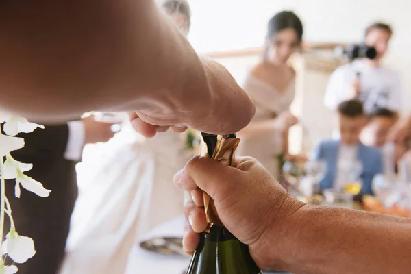Az ember megnyit egy üveg pezsgőt közel uo — Stock Fotó