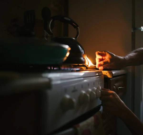 Um homem acende um fósforo num fogão a gás com fósforo. — Fotografia de Stock