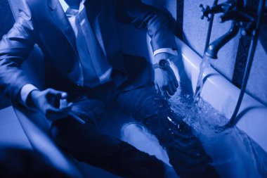 Takım elbiseli bir adam su banyosunda yatıyor..