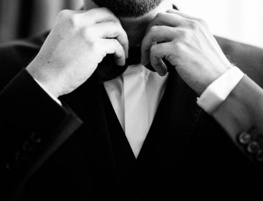 Takım elbiseli bir adam bir kelebeği düzeltir.