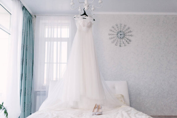 Белое свадебное платье висит в спальне. Белое платье невесты
