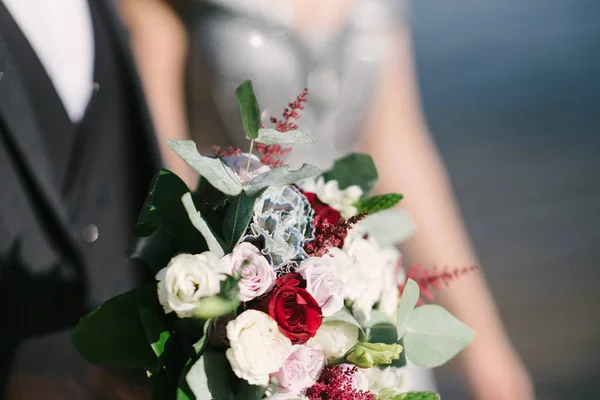 Mariée dans une robe de mariée tenant un bouquet de mariage dans ses mains gros plan — Photo