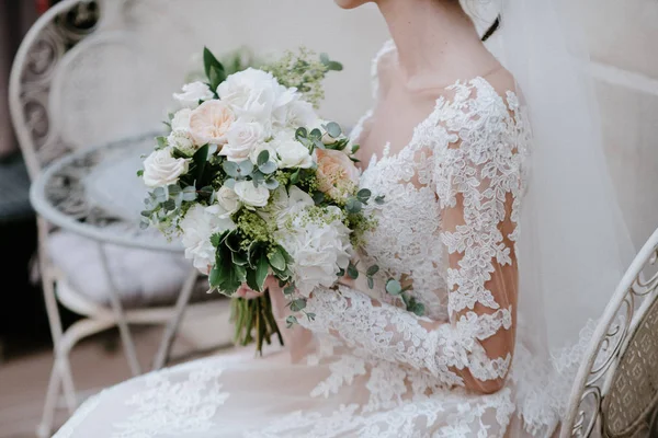 Nevěsta ve svatebních šatech s svatební kyticí v rukou zblízka — Stock fotografie