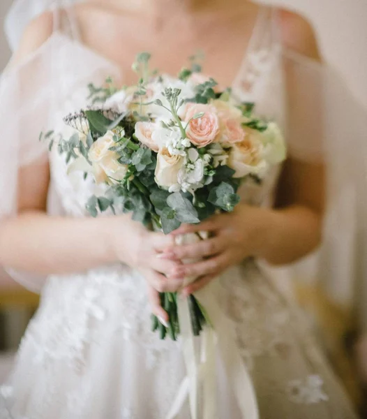 Bruid in een trouwjurk houden een bruiloft boeket in haar handen close-up — Stockfoto