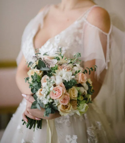 Mariée dans une robe de mariée tenant un bouquet de mariage dans ses mains gros plan — Photo