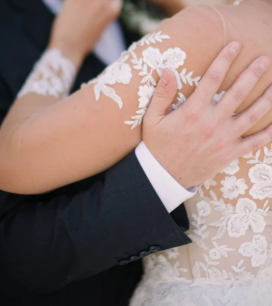 Le marié en costume étreint la mariée dans une robe de mariée — Photo