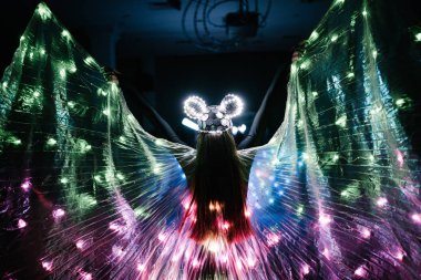 Parlak kostümlü insanlar karanlıkta dans ediyor.