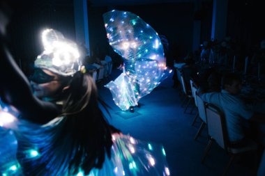 Parlak kostümlü insanlar karanlıkta dans ediyor.