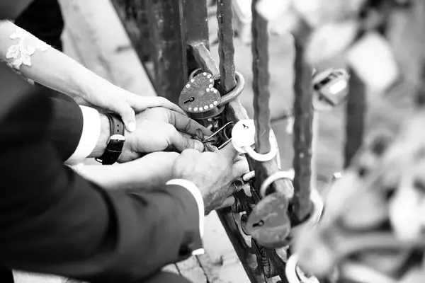 The groom hangs the castle on the bridge for the newlyweds. The wedding tradition. — Stock Photo, Image