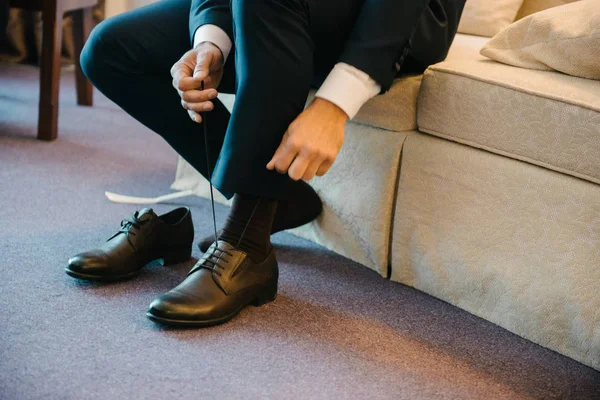 Um homem de fato põe sapatos nos pés . — Fotografia de Stock