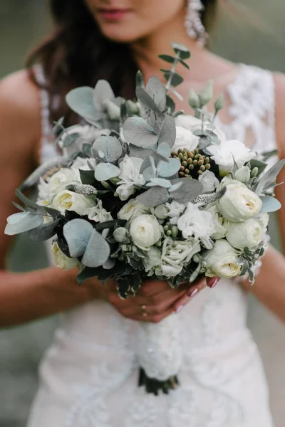 Nevěsta ve svatebních šatech s svatební kyticí v rukou zblízka — Stock fotografie