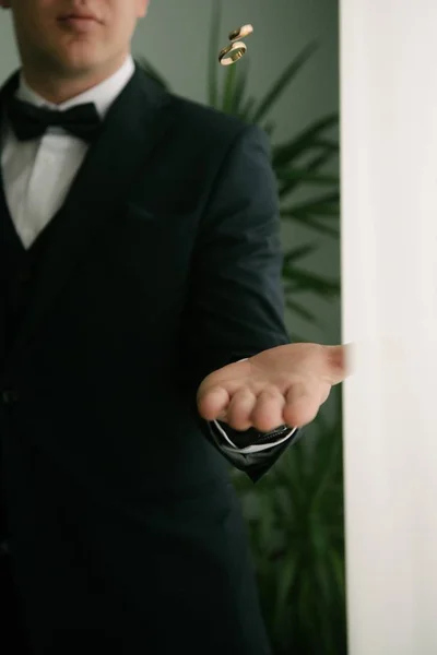 El novio vomita anillos de boda. Novio lanza anillos a mano —  Fotos de Stock