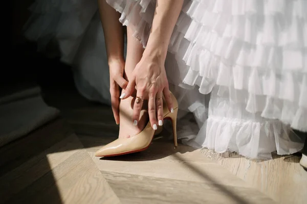 Невеста в свадебном платье надевает обувь на ноги — стоковое фото