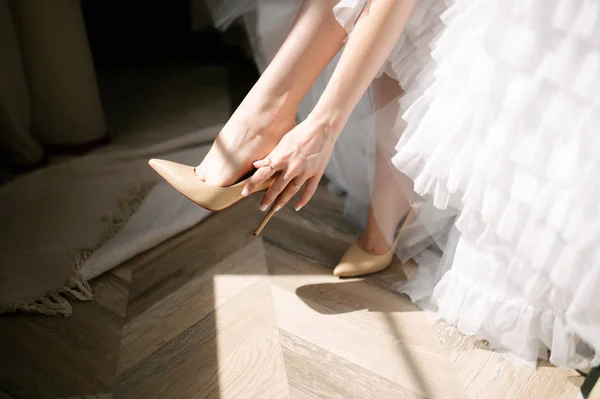 Невеста в свадебном платье надевает обувь на ноги — стоковое фото