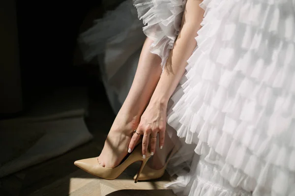 Bruid in een trouwjurk zet schoenen op haar voeten — Stockfoto