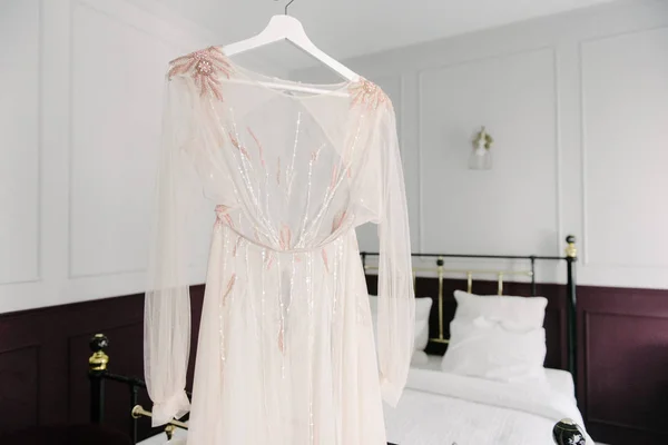 Λευκό νυφικό που κρέμεται στην κρεβατοκάμαρα. Λευκό φόρεμα νύφης — Φωτογραφία Αρχείου