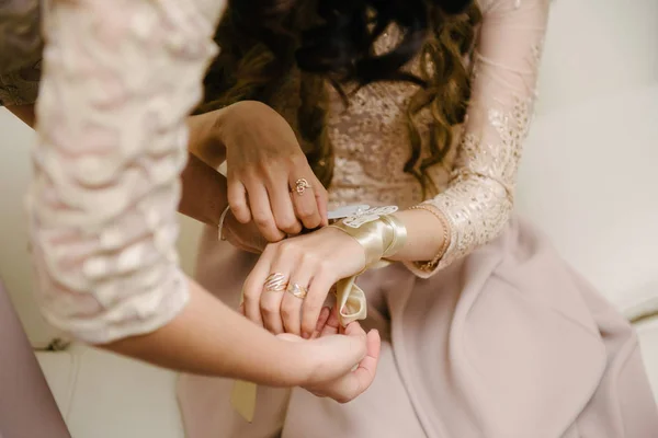 Bruid in een trouwjurk zet op haar arm een armband close-up — Stockfoto