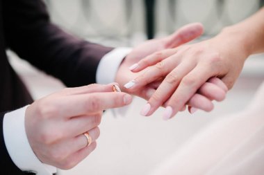 Damat geline yakın bir şekilde alyans takıyor. Gelin gelin gelinlik üzerine damat koyar.