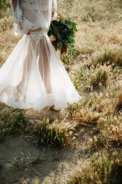 Mariée dans une robe de mariée tenant un bouquet de mariage dans ses mains gros plan — Photo