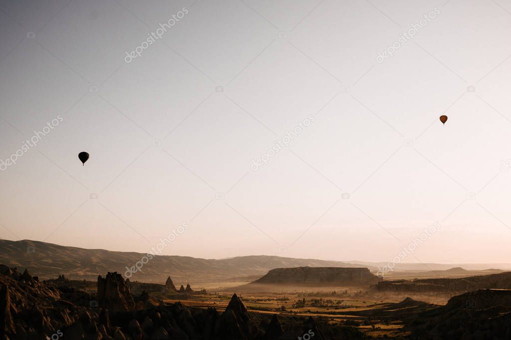 Hot air balloons landing in a mountain Cappadocia Goreme National Park Turkey.