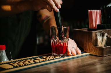 El barmen kokteyl yapmak. Kokteyl kiraz ve nane yaprakları var.