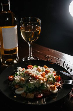 Siyah ahşap masada beyaz tabakta taze sezar salatası. Üst görünüm kopyalama alanı.