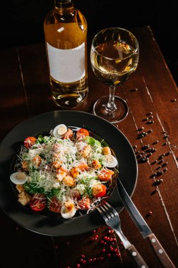 Siyah ahşap masada beyaz tabakta taze sezar salatası. Üst görünüm kopyalama alanı.