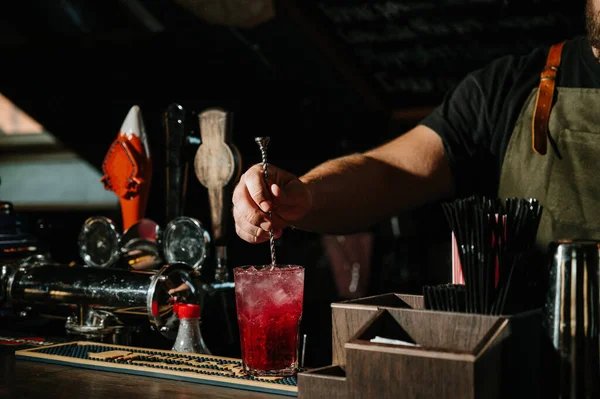 Bartender stirring a sweet and fresh pink summer cocktail in glass — Stock Photo, Image