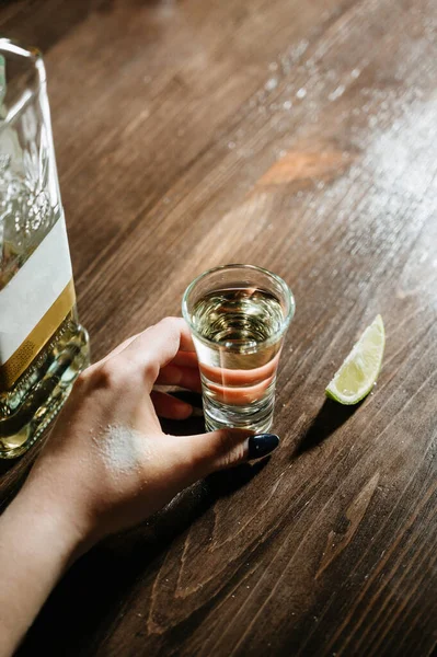 Hand with tequila shots on wooden tabletop — Stock Photo, Image