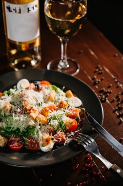 Siyah ahşap masada beyaz tabakta taze sezar salatası. Üst görünüm kopyalama alanı.