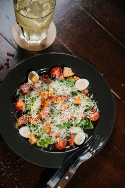 Siyah ahşap masada beyaz tabakta taze sezar salatası. Üst görünüm kopyalama alanı.