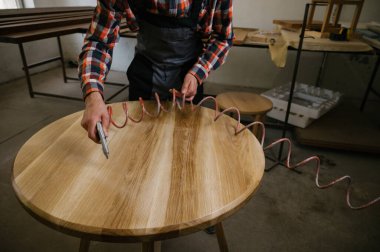 Marangozluk atölyesinde çalışma süreci. Tulumlu bir adam marangozluk atölyesinde çalışır. Meslek, marangozluk, marangozluk ve insan konsepti.