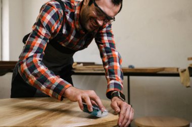 Marangozluk atölyesinde çalışma süreci. Tulumlu bir adam marangozluk atölyesinde çalışır. Meslek, marangozluk, marangozluk ve insan konsepti.