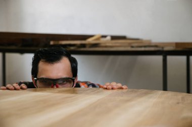 Marangozluk atölyesinde çalışma süreci. Tulumlu bir adam marangozluk atölyesinde çalışır. Meslek, marangozluk, marangozluk ve insan konsepti.