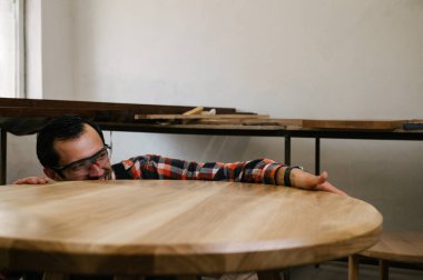 Marangozluk atölyesinde çalışma süreci. Tulumlu bir adam marangozluk atölyesinde çalışır. Meslek, marangozluk, marangozluk ve insan konsepti.