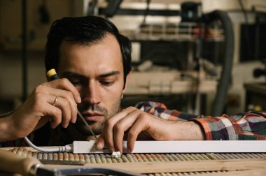 Marangozluk atölyesinde çalışma süreci. Tulumlu bir adam marangozluk atölyesinde çalışır. Meslek, marangozluk, marangozluk ve insan konsepti.