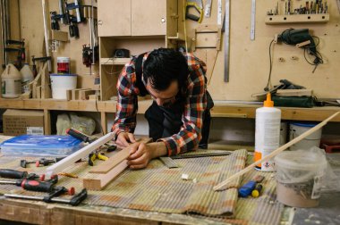 Marangozluk atölyesinde çalışma süreci. Tulumlu bir adam marangozluk atölyesinde çalışır. Meslek, marangozluk, marangozluk ve insan konsepti.