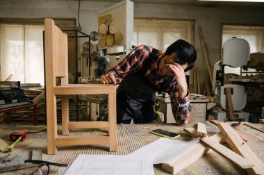 Marangozluk atölyesinde çalışma süreci. Tulumlu bir adam marangozluk atölyesinde çalışır. Meslek, marangozluk, marangozluk ve insan konsepti.