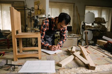 Marangozluk atölyesinde çalışma süreci. Tulumlu bir adam marangozluk atölyesinde çalışır. Meslek, marangozluk, marangozluk ve insan konsepti.