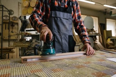 Marangozluk atölyesinde çalışma süreci. Elektrik Sander 'ı marangozluk atölyesinde marangozluk için kullanma. Meslek, marangozluk, marangozluk ve insan konsepti.