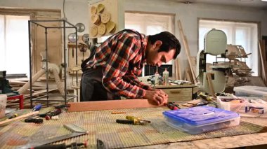 Marangozluk atölyesinde çalışma süreci. Tulumlu bir adam marangozluk atölyesinde çalışır. Meslek, marangozluk, marangozluk ve insan konsepti.