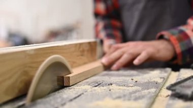 Marangozluk atölyesinde çalışma süreci. Marangozluk atölyesinde çalışan bir adam. Marangoz, kereste fabrikasında tahta kesmek için testere makinesi kullanıyor. Meslek, marangozluk, marangozluk, marangozluk.