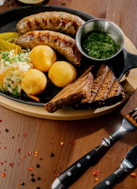 Tavada kızarmış sosisli kızarmış patates ve çatal bıçak takımı, üst manzara. Alman gıda konsepti