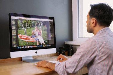 Profesyonel Fotoğrafçı Fotoğraf Düzenleme Uygulamasında çalışıyor. Kişisel Bilgisayarındaki Yazılım. Fotoğrafları işlemek için fotoğrafçı. Fotoğraf ekipmanları masanın üstünde. Resimler yeniden yükleniyor.
