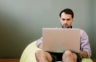 Evde dizüstü bilgisayar kullanan mutlu bir adam. Evde dizüstü bilgisayarda çalışan mutlu bir adam. İnternet bankacılığı hizmetini kullanan mutlu bir erkek.