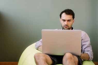 Evde dizüstü bilgisayar kullanan mutlu bir adam. Evde dizüstü bilgisayarda çalışan mutlu bir adam. İnternet bankacılığı hizmetini kullanan mutlu bir erkek.