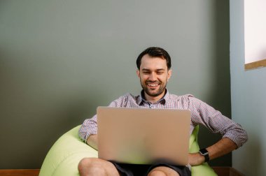 Evde dizüstü bilgisayar kullanan mutlu bir adam. Evde dizüstü bilgisayarda çalışan mutlu bir adam. İnternet bankacılığı hizmetini kullanan mutlu bir erkek.