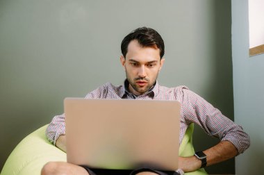 Evde dizüstü bilgisayar kullanan mutlu bir adam. Evde dizüstü bilgisayarda çalışan mutlu bir adam. İnternet bankacılığı hizmetini kullanan mutlu bir erkek.